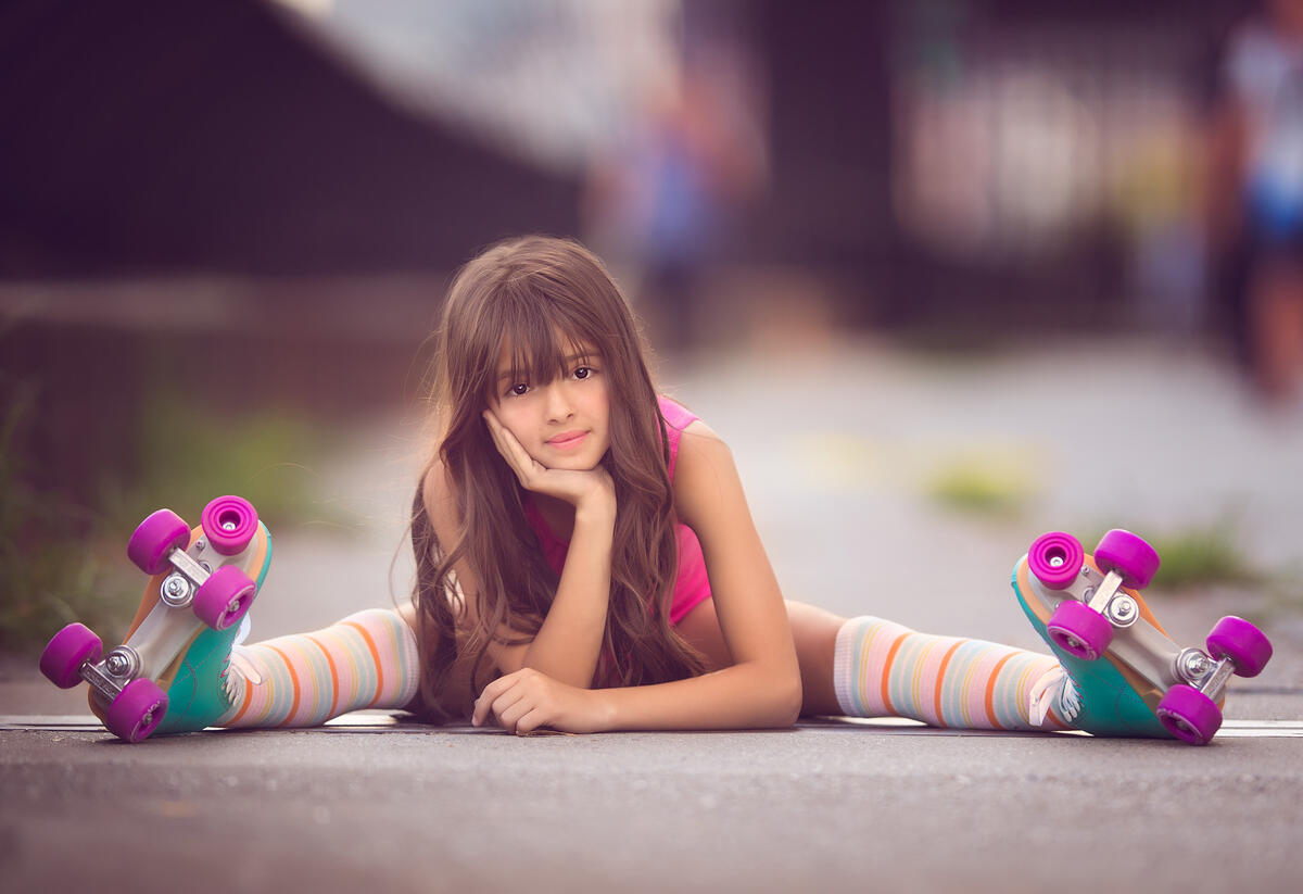 Cute girl sitting on the pavement on roller skates