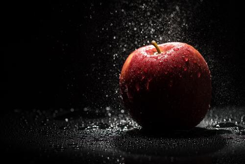 Apple and water drops on black background
