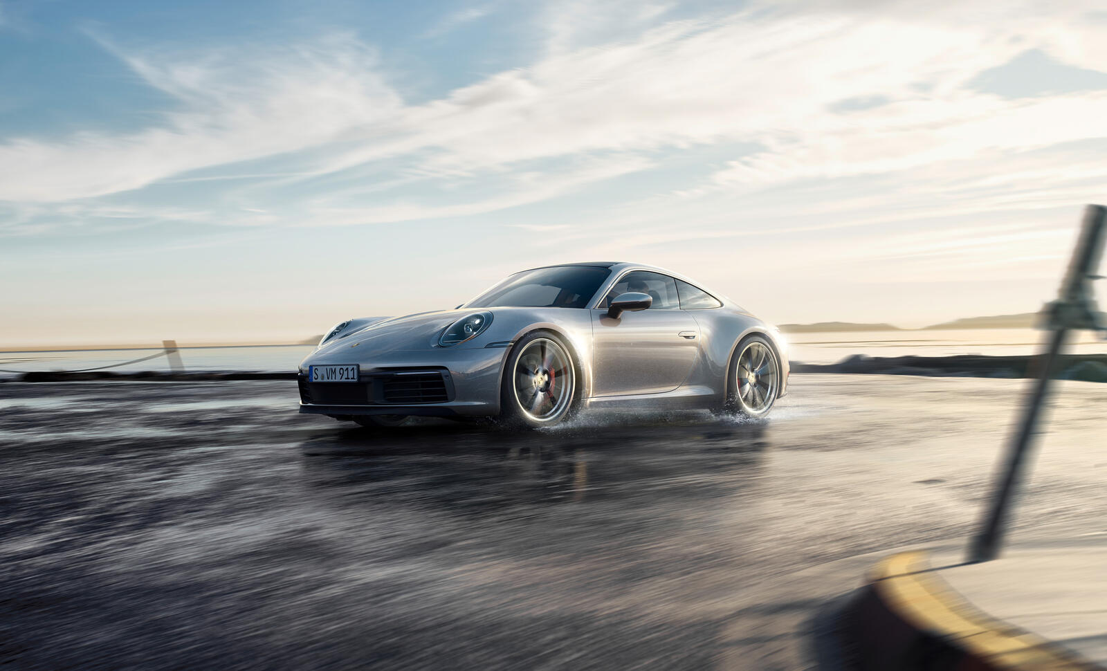 Бесплатное фото Porsche 911 едет по дороге с лужами