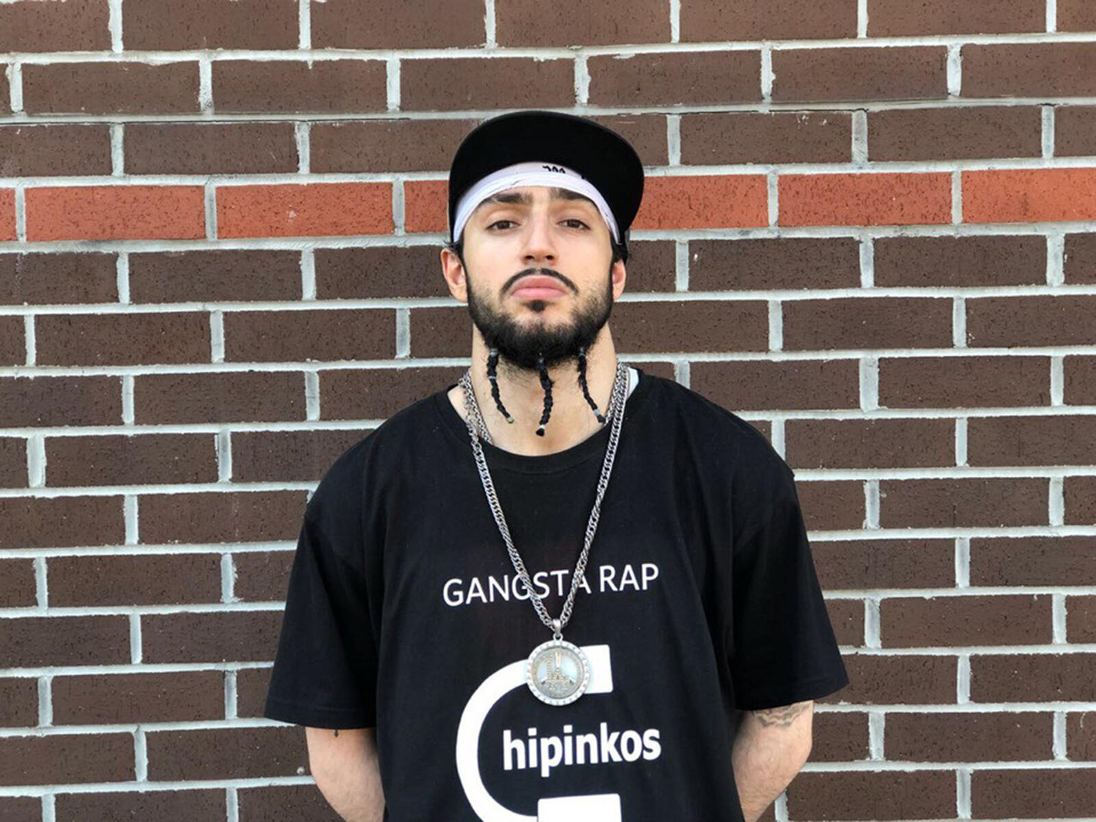 Free photo Gangsta rapper standing near a brick wall