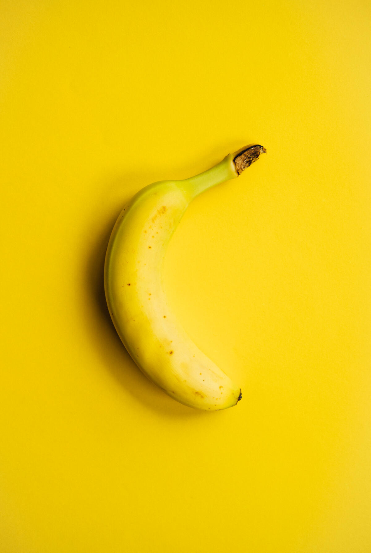Желтый банан на желтом фоне