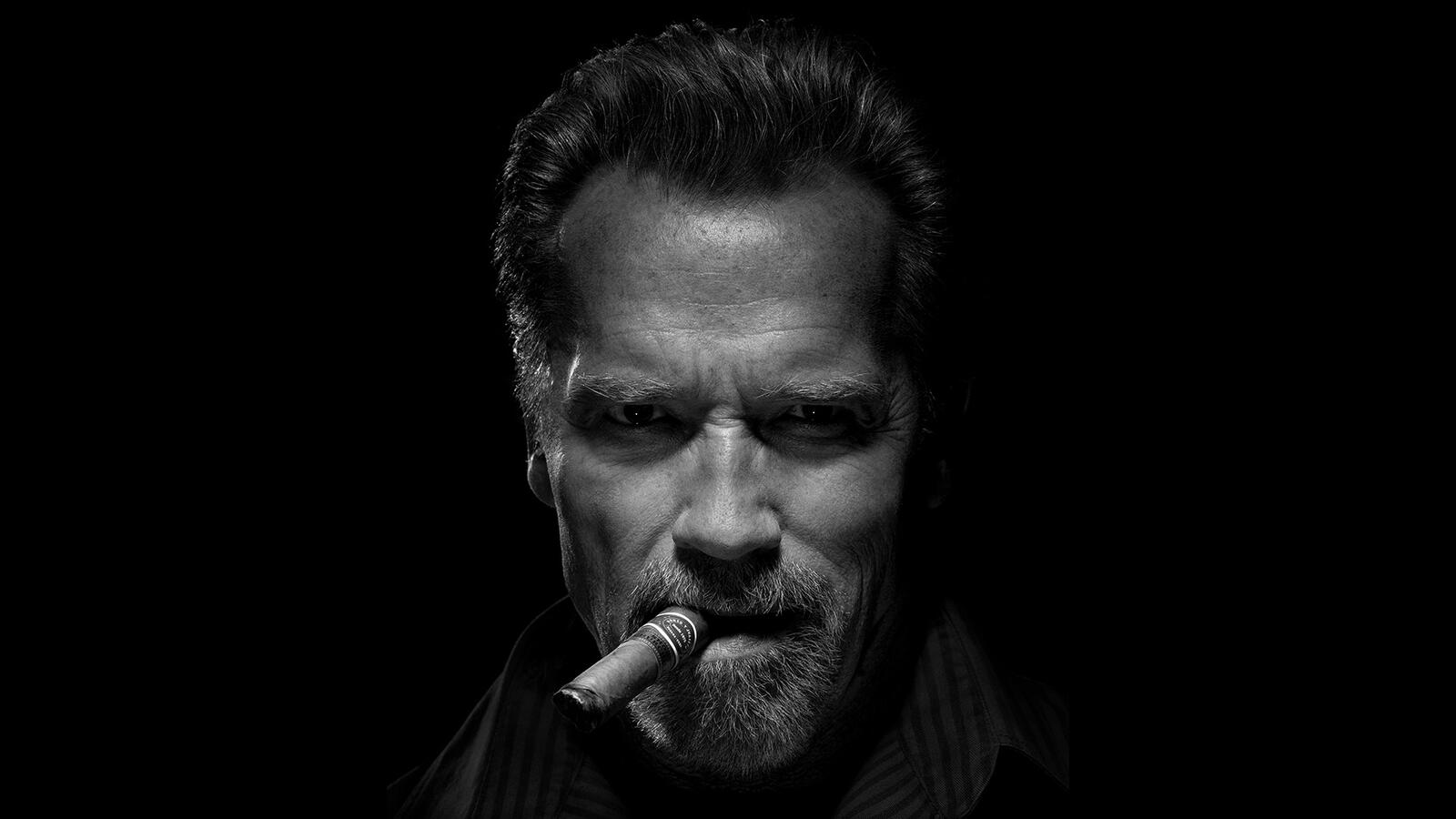 Бесплатное фото Арнольд Шварценеггер с сигарой на черном фоне