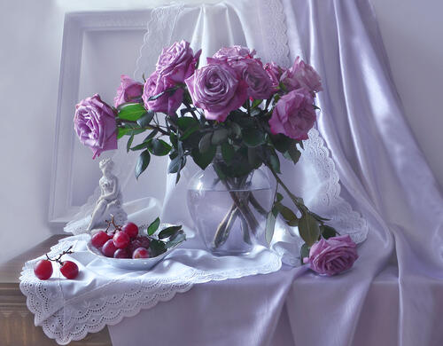 Фиолетовые розы в прозрачной вазе стоят на столе