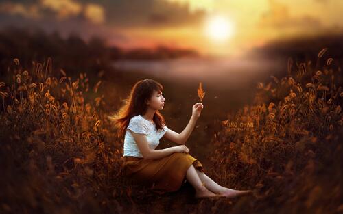 Китаянка с цветком на фоне заката солнца