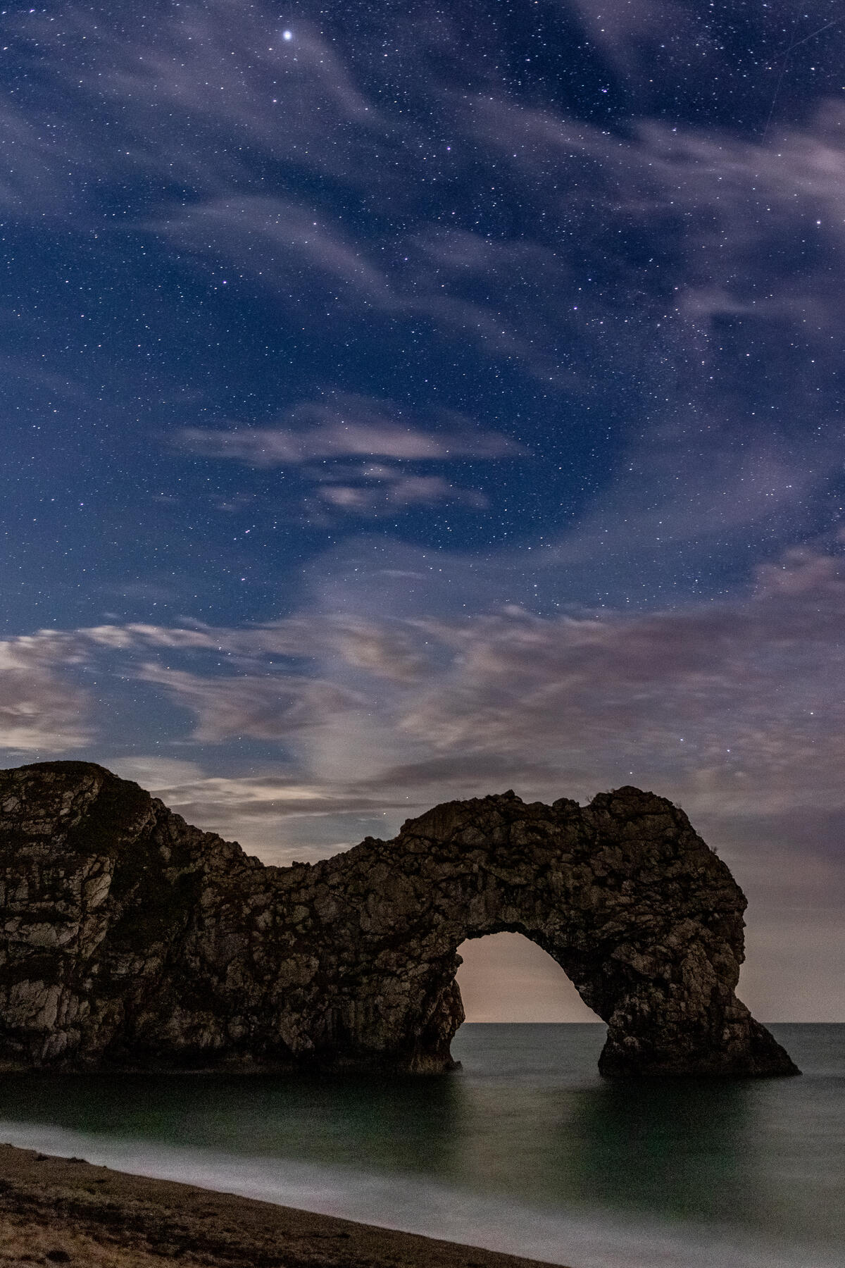 Rock with an arch on the seashore at sunset