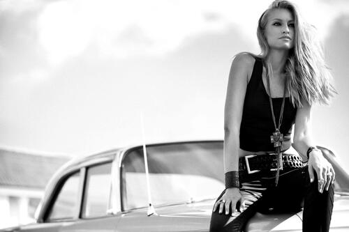 Victoria Alervall poses by a car in a black and white photo