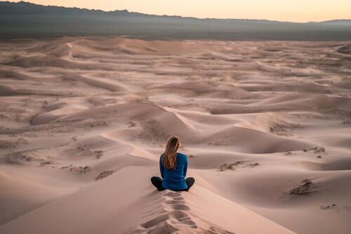 A girl sits on a sandy ridge