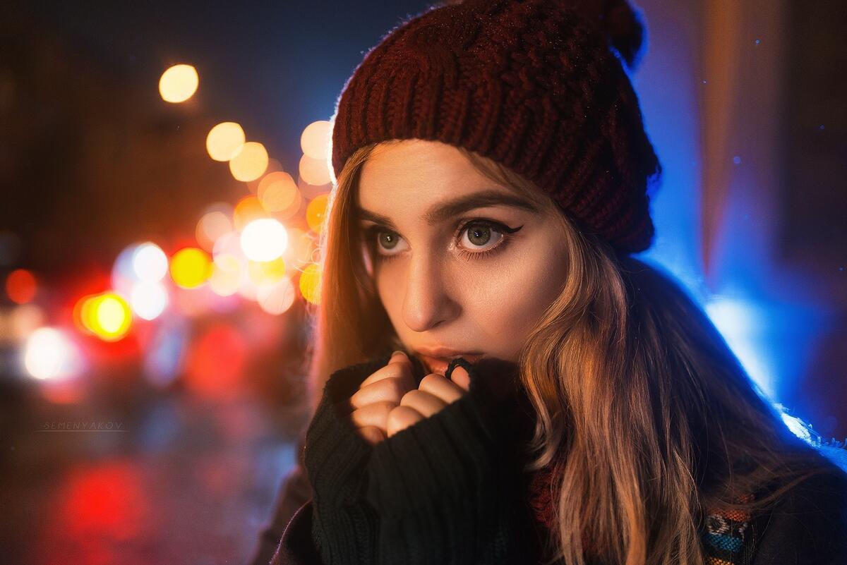 Девушка в шапке держит руки у лица от холода