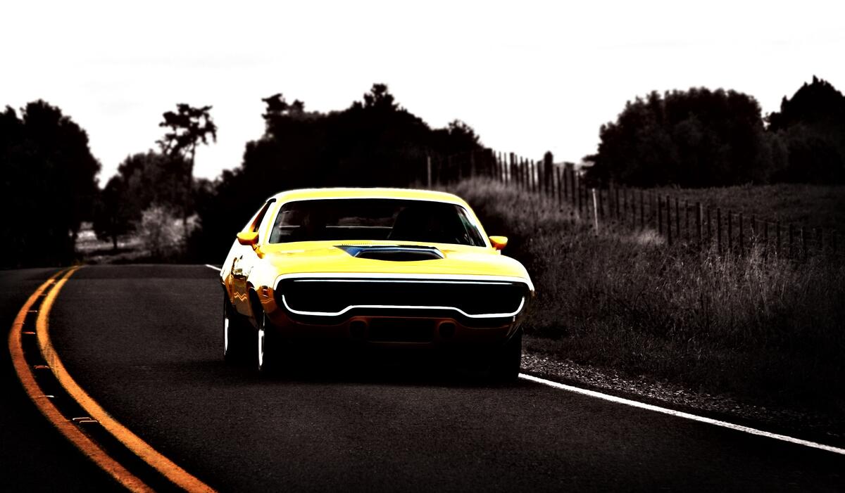 A yellow Plymouth GTX driving down the road.