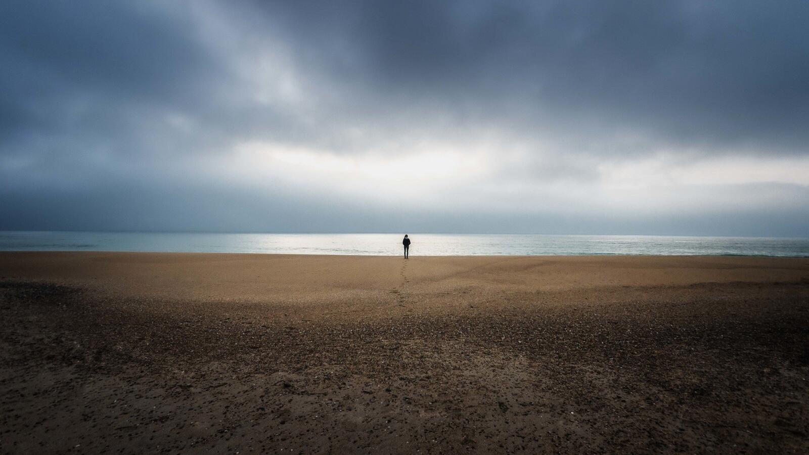 Бесплатное фото Одинокий мужчина на большом пляже у моря